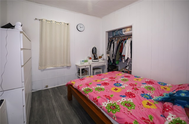 bedroom featuring dark hardwood / wood-style floors, wooden walls, and a closet