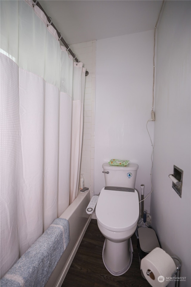 bathroom with hardwood / wood-style floors, shower / bath combo with shower curtain, and toilet