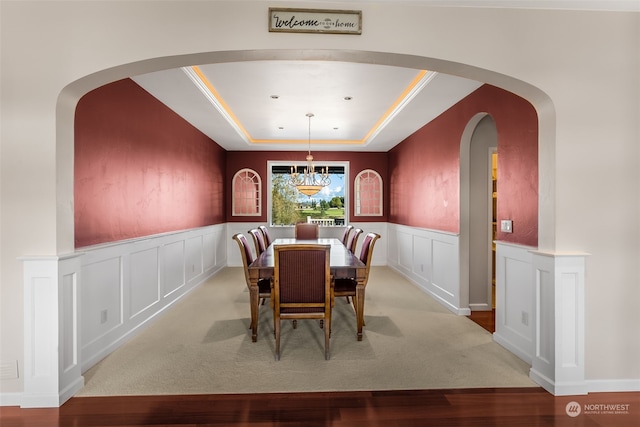 dining space with a chandelier, light hardwood / wood-style flooring, and a tray ceiling