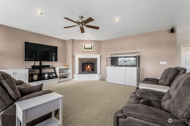 carpeted living room with a fireplace and ceiling fan