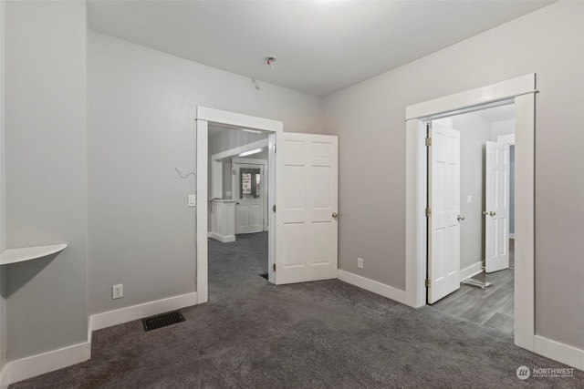 unfurnished room featuring dark colored carpet