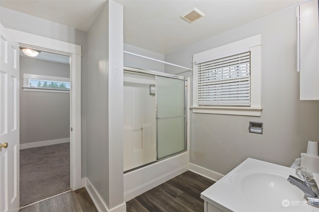 bathroom featuring bath / shower combo with glass door, hardwood / wood-style floors, vanity, and plenty of natural light