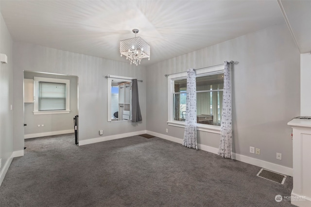 carpeted empty room featuring a notable chandelier and a healthy amount of sunlight