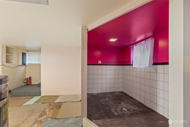 bathroom featuring water heater and tile walls