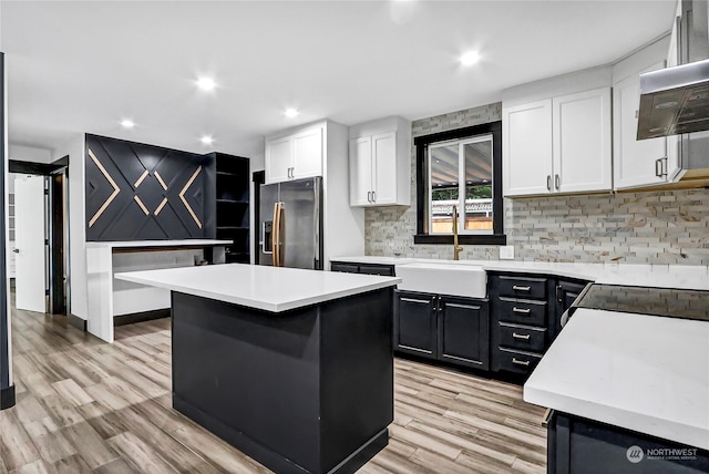 kitchen with light hardwood / wood-style floors, stainless steel refrigerator with ice dispenser, white cabinetry, and a kitchen island