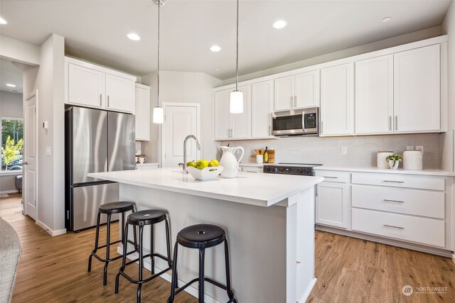 kitchen with white cabinetry, light wood-type flooring, stainless steel appliances, and pendant lighting