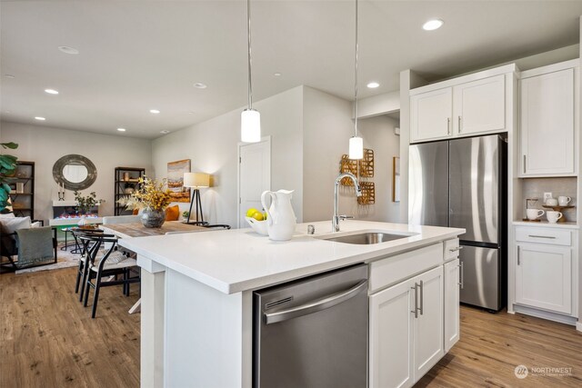 kitchen featuring white cabinetry, appliances with stainless steel finishes, sink, and decorative light fixtures