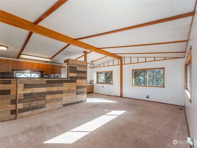 carpeted living room with beam ceiling, high vaulted ceiling, and wooden walls