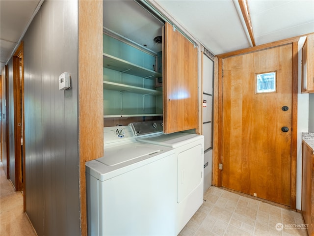 laundry area featuring wooden walls and washing machine and dryer