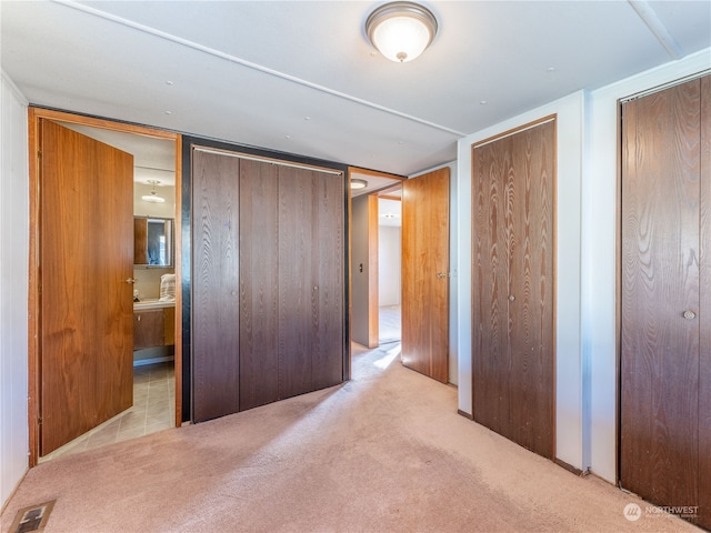 carpeted bedroom featuring ensuite bath and multiple closets