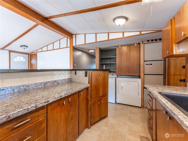 kitchen with sink, light stone counters, separate washer and dryer, and vaulted ceiling with beams