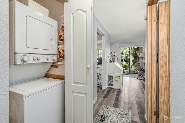 laundry area featuring hardwood / wood-style flooring and stacked washing maching and dryer