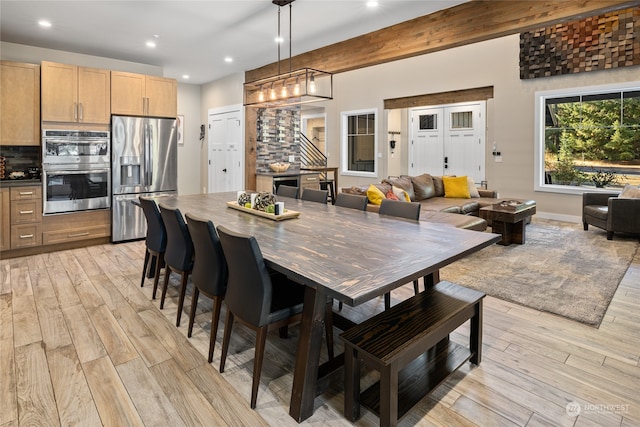 dining area featuring beam ceiling and light hardwood / wood-style flooring