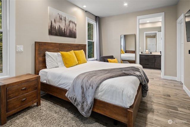 bedroom featuring ensuite bathroom and light hardwood / wood-style flooring