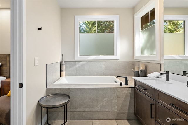 bathroom with vanity, a relaxing tiled tub, and tile patterned floors