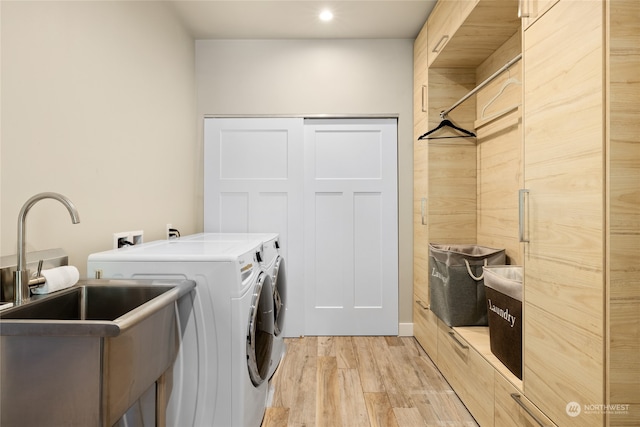 clothes washing area featuring sink, light hardwood / wood-style flooring, and separate washer and dryer