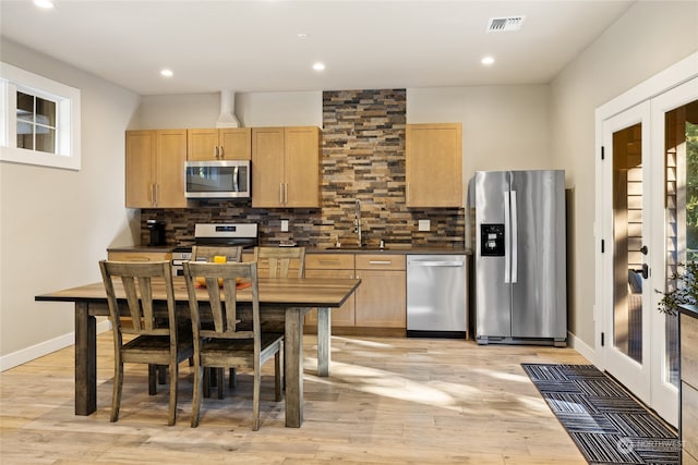 kitchen featuring tasteful backsplash, light brown cabinetry, sink, light wood-type flooring, and stainless steel appliances