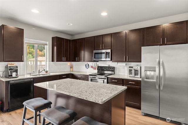 kitchen with light hardwood / wood-style flooring, a breakfast bar, stainless steel appliances, and a kitchen island