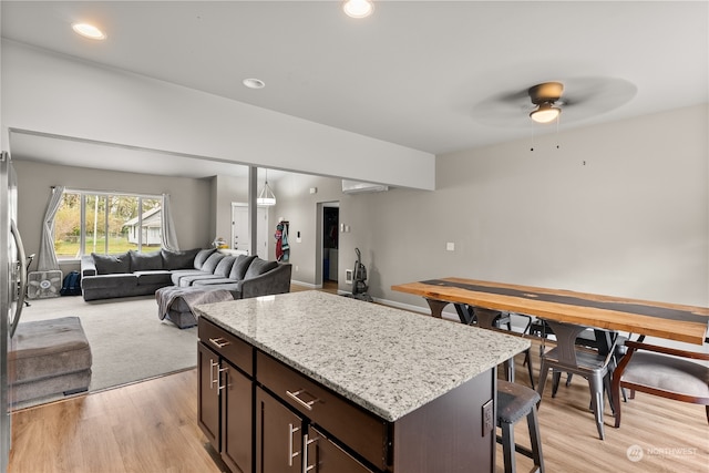 kitchen with light wood-type flooring, a center island, stainless steel fridge, ceiling fan, and dark brown cabinetry