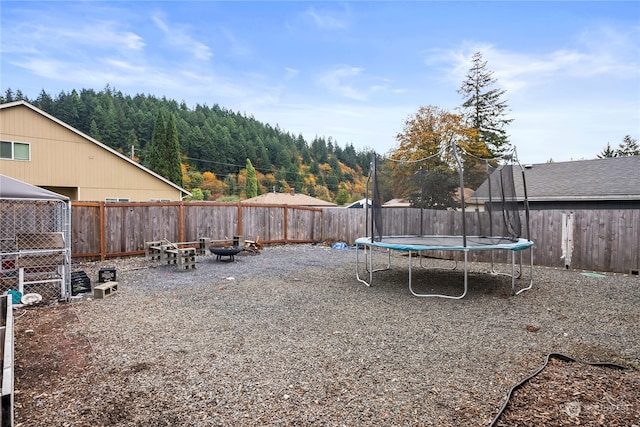 view of yard with an outdoor fire pit and a trampoline