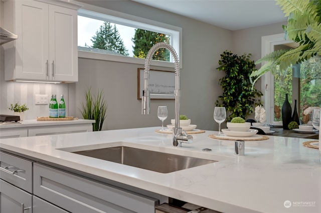 kitchen with white cabinetry, plenty of natural light, sink, and light stone countertops