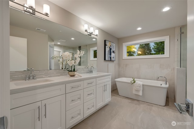 bathroom featuring tile walls, decorative backsplash, a washtub, and vanity