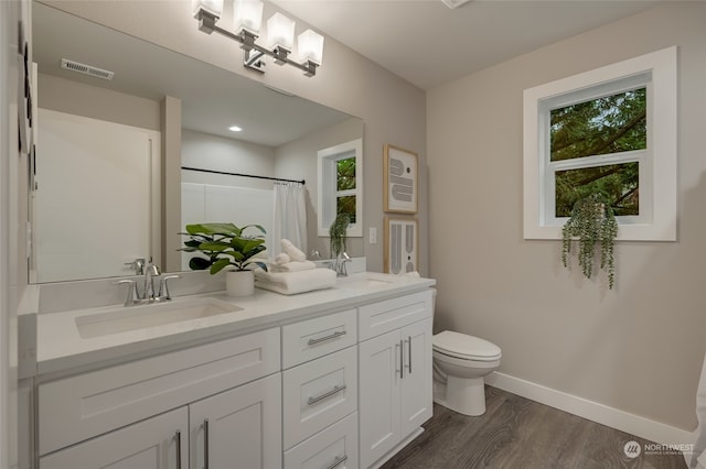 bathroom with walk in shower, hardwood / wood-style floors, a wealth of natural light, and toilet