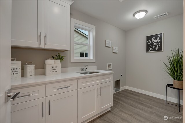 clothes washing area featuring hookup for a washing machine, cabinets, sink, light hardwood / wood-style floors, and electric dryer hookup