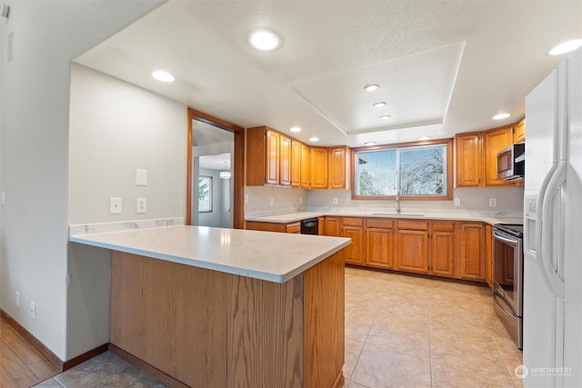 kitchen featuring sink, light tile patterned floors, stainless steel appliances, a tray ceiling, and kitchen peninsula