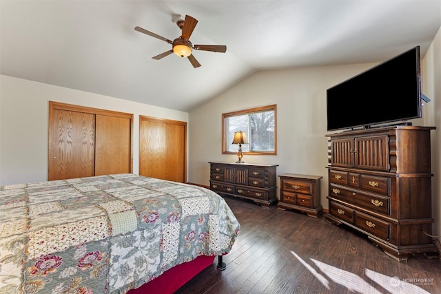 bedroom featuring ceiling fan, dark hardwood / wood-style floors, vaulted ceiling, and two closets