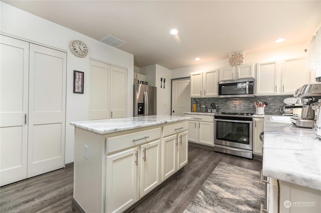 kitchen featuring dark hardwood / wood-style flooring, a kitchen island, light stone counters, and stainless steel appliances