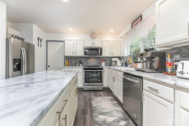 kitchen featuring dark hardwood / wood-style flooring, white cabinets, sink, backsplash, and appliances with stainless steel finishes