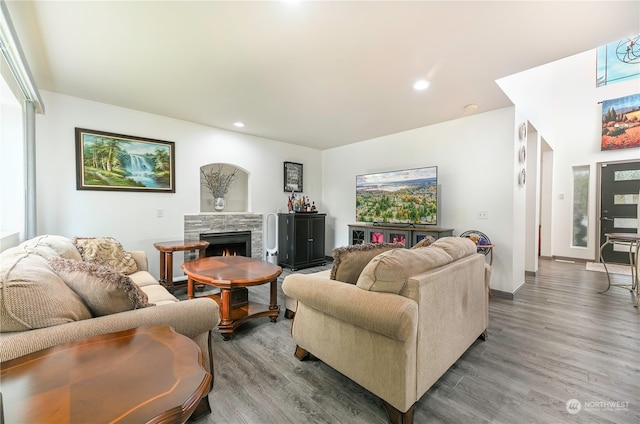 living room with a stone fireplace and hardwood / wood-style flooring