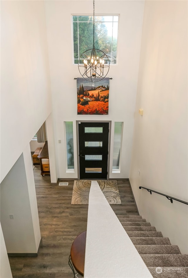 foyer featuring a towering ceiling, dark wood-type flooring, and a notable chandelier