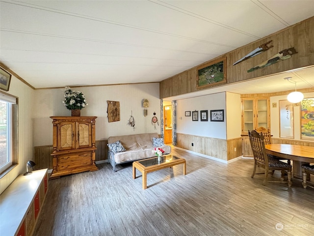 living room featuring crown molding, hardwood / wood-style flooring, vaulted ceiling, and wood walls