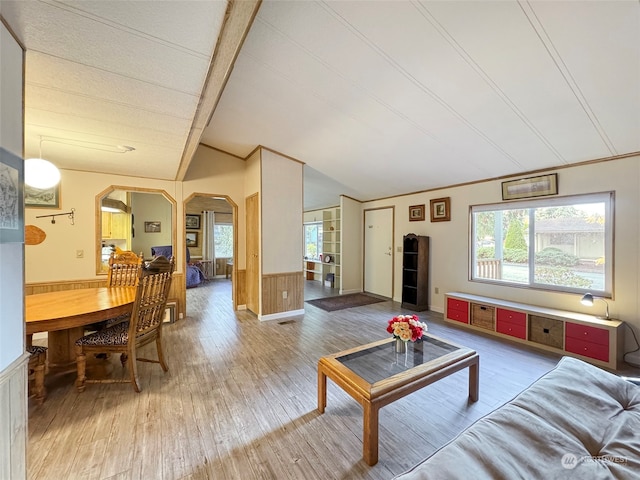 living room featuring lofted ceiling, hardwood / wood-style flooring, and wood walls