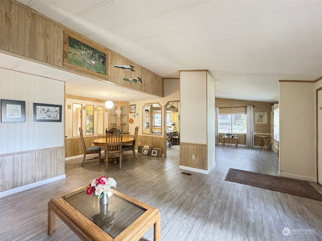 living room featuring wood walls, wood-type flooring, and lofted ceiling