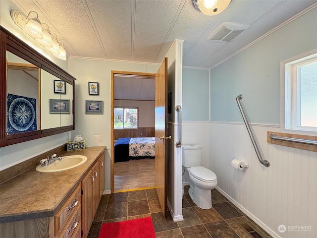 bathroom with vanity, toilet, crown molding, and a textured ceiling