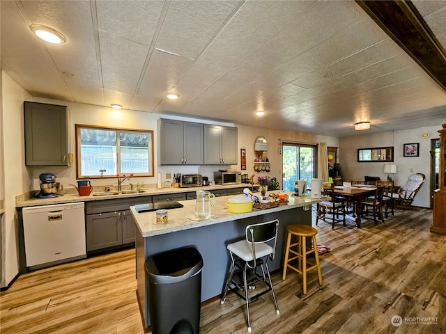 kitchen featuring a breakfast bar area, dishwasher, a center island, and light hardwood / wood-style flooring