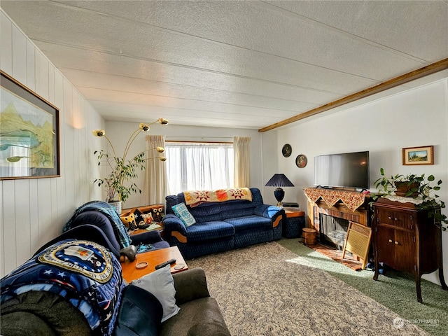 living room featuring wood walls, carpet flooring, a textured ceiling, and a fireplace