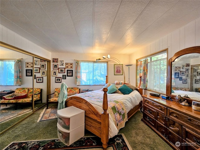 carpeted bedroom with wooden walls and a textured ceiling