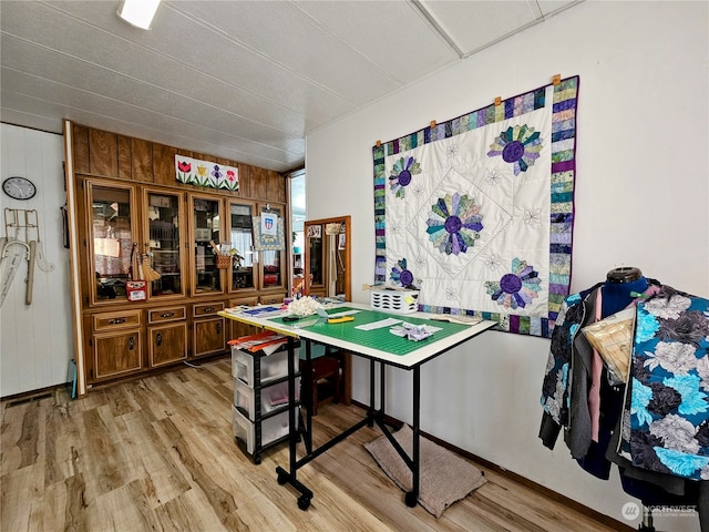 game room featuring light hardwood / wood-style flooring and wooden walls