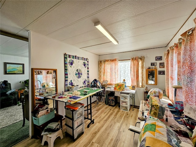 interior space with a textured ceiling, light wood-type flooring, and wood walls