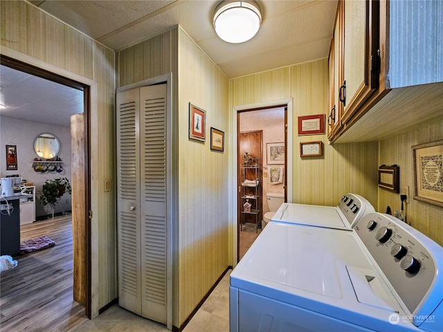 laundry area featuring light hardwood / wood-style floors, cabinets, and washer and clothes dryer