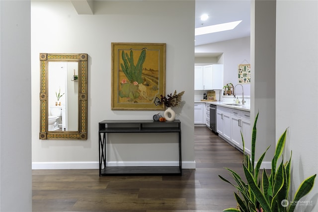 hallway featuring vaulted ceiling with skylight, dark hardwood / wood-style floors, and sink