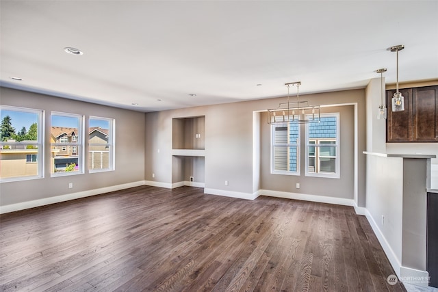 unfurnished living room with a notable chandelier and dark wood-type flooring