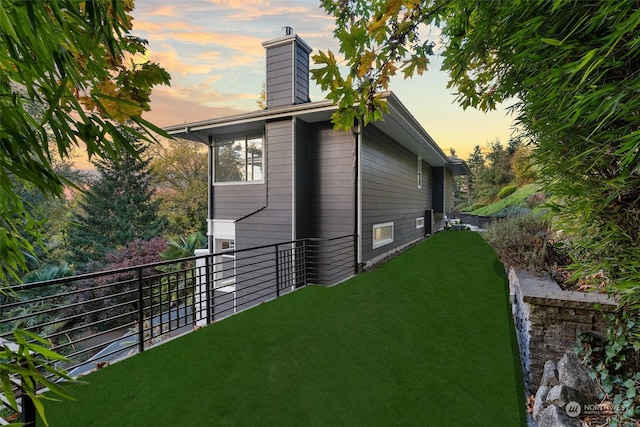 property exterior at dusk with a yard and a balcony