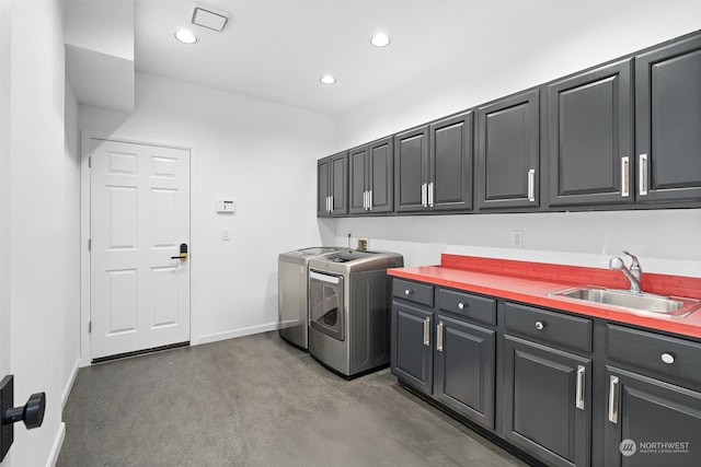 clothes washing area featuring sink, cabinets, and washer and dryer