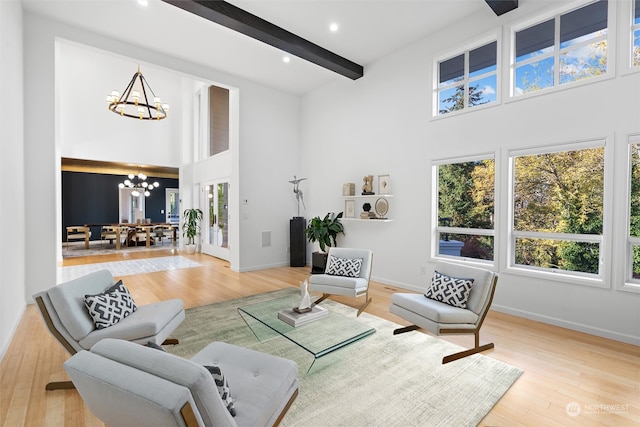 living room with beam ceiling, hardwood / wood-style floors, a chandelier, and a high ceiling