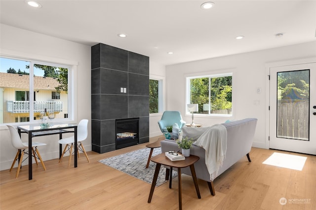 living room featuring a tiled fireplace and light wood-type flooring